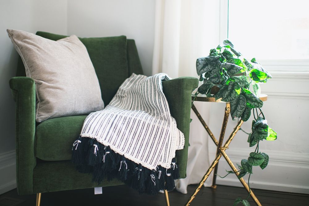 Green velvet lounge chair with a striped throw